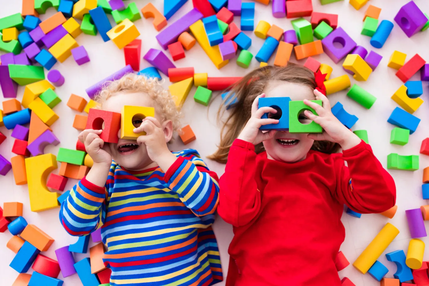 A happy toddler playing with colourful wooden blocks